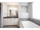Bright bathroom featuring a soaking tub, modern vanity with dark countertops, and large mirrored backsplash at 15694 Provincial Ln, Fishers, IN 46040