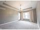 Expansive bedroom with plush carpet, tray ceiling, and a modern chandelier hanging from the ceiling at 15694 Provincial Ln, Fishers, IN 46040