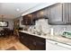 Classic kitchen featuring dark cabinets, stone countertops, backsplash, and stainless steel sink at 2456 N Willow Way, Indianapolis, IN 46268