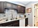 Well-lit kitchen with dark wood cabinets, stainless steel sink, and backsplash at 2456 N Willow Way, Indianapolis, IN 46268