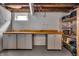 Basement workshop area with cabinets, countertop, window, and storage shelving at 3416 Guilford Ave, Indianapolis, IN 46205