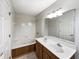 Well-lit bathroom featuring a soaking tub, tiled shower, double sink vanity, and white cabinets at 5107 Stirling Point Dr, Indianapolis, IN 46241
