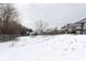Wide view of backyard with fencing, small trampoline, winter grass, and a cozy patio area at 5443 Alcott Ln, Indianapolis, IN 46221