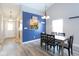 Dining room with view into kitchen, featuring a blue accent wall and hardwood style flooring at 5443 Alcott Ln, Indianapolis, IN 46221