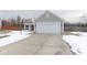 View of a single-story home with a spacious driveway and attached two-car garage, set against a cloudy sky at 5443 Alcott Ln, Indianapolis, IN 46221