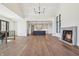Bright living room featuring a fireplace, sleek hardwood floors, large windows, a modern chandelier, and an open-concept to kitchen at 580 Exmoor Dr, Carmel, IN 46032