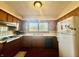 Traditional eat-in kitchen with warm wood cabinetry, vintage wallpaper, and a window above the sink at 6346 Shelby St, Indianapolis, IN 46227