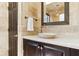 Half bath with a granite countertop, decorative travertine walls, and an ornate mirror at 645 Ellsworth St, Indianapolis, IN 46202