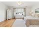 Bright bedroom with hardwood floors, a ceiling fan, a large window with curtains, and a neutral-toned bed at 645 Ellsworth St, Indianapolis, IN 46202