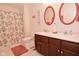 Full bathroom showcasing a dual-sink vanity, a shower with floral curtain, and round mirrors at 10120 Youngwood Ln, Fishers, IN 46038