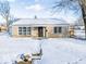 Cozy brick home featuring a covered porch and snow-covered lawn at 1239 Brooks St, Indianapolis, IN 46202