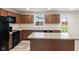 Bright kitchen featuring an island, dark cabinets, and modern black appliances at 13860 N Tiosa Ln, Camby, IN 46113
