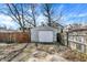 View of the detached garage in the backyard with peeling paint, an ADT security sign, and mature trees at 139 S Ritter Ave, Indianapolis, IN 46219