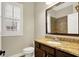 Bathroom featuring a granite countertop, wooden cabinets, white toilet and framed mirror above a sink at 15745 Market Center Dr, Carmel, IN 46033