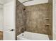 Bathroom with a white bathtub and tiled walls, featuring a shower head and shelves at 15745 Market Center Dr, Carmel, IN 46033