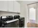 Modern laundry room with front load washer and dryer, plus white cabinets at 15745 Market Center Dr, Carmel, IN 46033