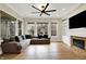 Inviting living room with a fireplace, large windows, hardwood floors, and modern ceiling fan at 15745 Market Center Dr, Carmel, IN 46033