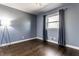 Simple bedroom featuring hardwood floors, a large window with curtains, and a floor lamp at 320 E 86Th St, Indianapolis, IN 46240