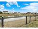 Scenic view of a community pond surrounded by homes with well-maintained lawns and a secure black chain link fence at 4318 Ballybay Ln, Indianapolis, IN 46239