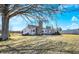 Inviting home exterior with a stone chimney, a patio area, and a sprawling yard with mature trees, offering a tranquil setting at 5420 W Goeller W Rd, Columbus, IN 47201