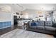 Open-concept living space with hardwood floors, a cozy gray sofa, and a clear view of the kitchen and dining area at 10373 Cerulean Dr, Noblesville, IN 46060