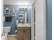 Bathroom featuring blue walls, a wood vanity with a white sink, and modern fixtures at 10613 Glenayr Dr, Camby, IN 46113