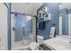 Modern bathroom featuring an updated shower with a glass door, blue patterned accent wall, and white fixtures at 10613 Glenayr Dr, Camby, IN 46113