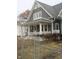 Charming gray home featuring a covered front porch with decorative white columns and a well-manicured, yet dormant, lawn at 21 S Warman Ave, Indianapolis, IN 46222