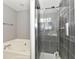 Modern bathroom featuring a bathtub, glass-enclosed shower with gray tile, and convenient built-in shelves at 3873 Crest Point Dr, Noblesville, IN 46062