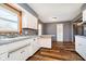 Kitchen area featuring white cabinets, mosaic backsplash, stylish wood-look flooring, and a cozy nook at 4812 Southview Dr, Anderson, IN 46013