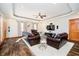 Spacious living room with a tray ceiling, dark wood furnishings, and a walk-out to the patio at 5079 Stonespring Way, Anderson, IN 46012