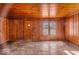 This wood-paneled living room features vintage flooring and a sun-filled window showcasing the home's exterior at 7016 Evanston Ave, Indianapolis, IN 46220