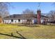 View of the home's exterior and large backyard with mature trees and a brick chimney at 7844 N Audubon Rd, Indianapolis, IN 46250