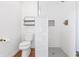 Elegant bathroom with a toilet, floating shelves, and a tiled shower with mosaic accents at 7844 N Audubon Rd, Indianapolis, IN 46250