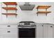Stainless steel oven below stainless steel vent hood, surrounded by open wood shelving and white cabinets at 7844 N Audubon Rd, Indianapolis, IN 46250