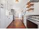 Bright kitchen boasts white cabinets, marble countertops, stainless steel appliances, open shelving, and hardwood floors at 7844 N Audubon Rd, Indianapolis, IN 46250