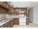 Traditional kitchen featuring wood cabinetry, stone backsplash, laminate counters, and classic white appliances at 8139 Laughlin Dr, Indianapolis, IN 46219