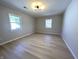 Bright bedroom with two windows, light walls, and neutral-toned wood floors at 8315 Woodall Dr, Indianapolis, IN 46268