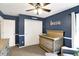 Bedroom with blue walls, a wood crib, and a chair and ottoman at 11185 Beardsley Way, Fishers, IN 46038