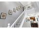 Hallway with staircase, showcasing stylish wall decor and a glimpse into the kitchen with stainless steel appliances at 11185 Beardsley Way, Fishers, IN 46038