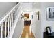 Hallway and staircase view with wood floors and a glimpse of the kitchen with a breakfast bar at 11185 Beardsley Way, Fishers, IN 46038