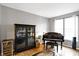Sunlit living room showcasing a piano, display cabinet, and hardwood floors at 11185 Beardsley Way, Fishers, IN 46038