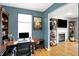 Home office with custom shelving, hardwood floors, decoratively painted walls, and a glimpse into the living room at 11185 Beardsley Way, Fishers, IN 46038