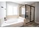 Modern bathroom featuring a tub, a glass-enclosed shower, and neutral-toned tiles and decorative accents at 12650 Misty Ridge Ct, Fishers, IN 46037