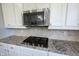 Close-up of kitchen details showcasing gas cooktop, tile backsplash, and granite countertops at 12650 Misty Ridge Ct, Fishers, IN 46037