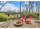 Cozy backyard fire pit area with pea gravel, surrounded by two red Adirondack chairs at 17420 Dalton Ct, Noblesville, IN 46062