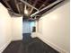 Finished basement area with white walls, black rubber flooring, and visible ceiling beams and ductwork at 1818 N Cornell Ave, Indianapolis, IN 46202