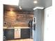 Modern kitchen features stainless steel appliances and brick accent wall with open shelving at 230 E 9Th St # 506, Indianapolis, IN 46204