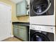 This laundry room features green cabinets, black countertops and stacked white front load washer and dryer at 4139 Bella Ct, Indianapolis, IN 46237