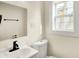 Bright bathroom with a white toilet, sink, black hardware, and a window at 462 W Broadway St, Greenwood, IN 46142